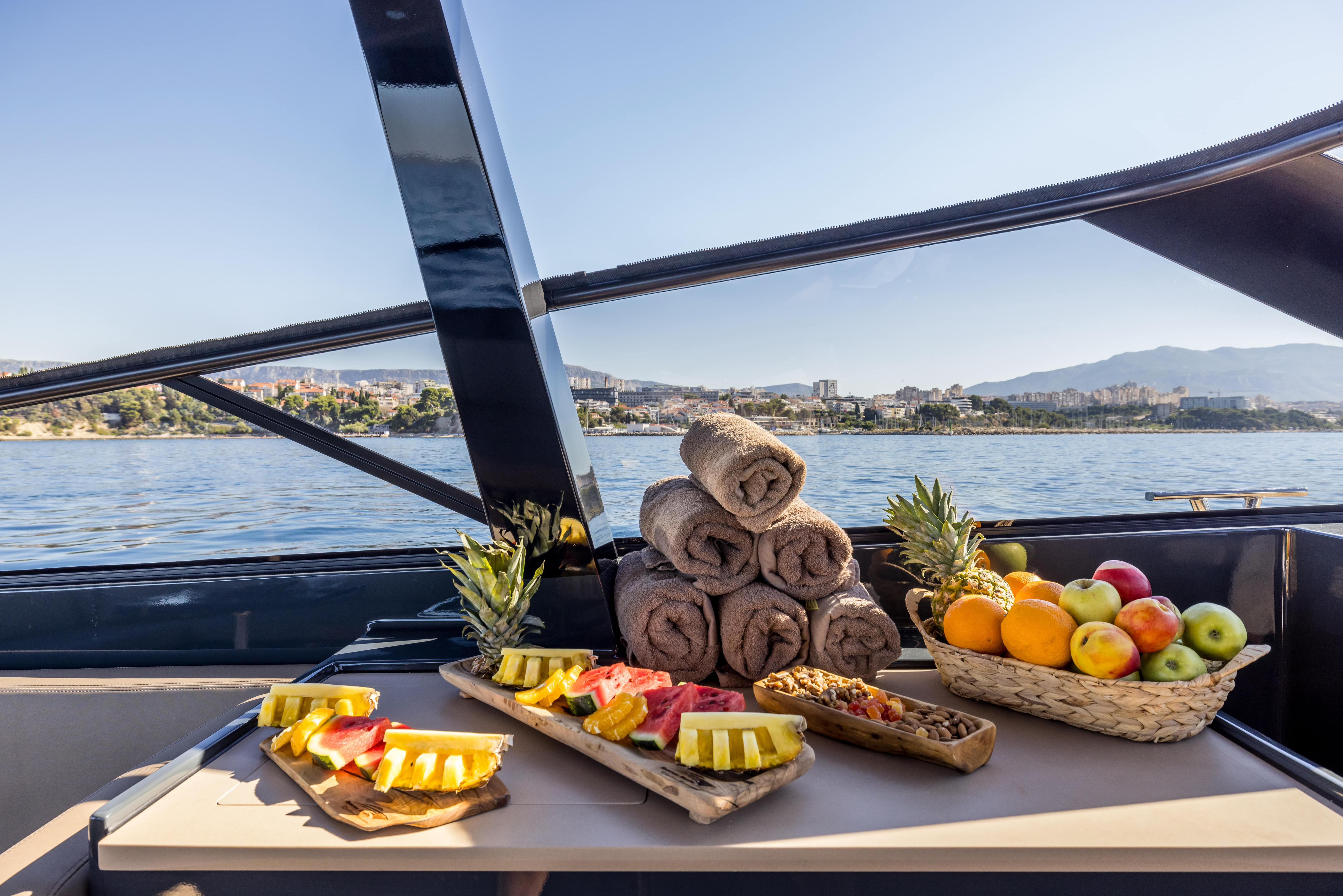 Interior view of Colnago 45 boat with fruits and towels arranged near a scenic water view.