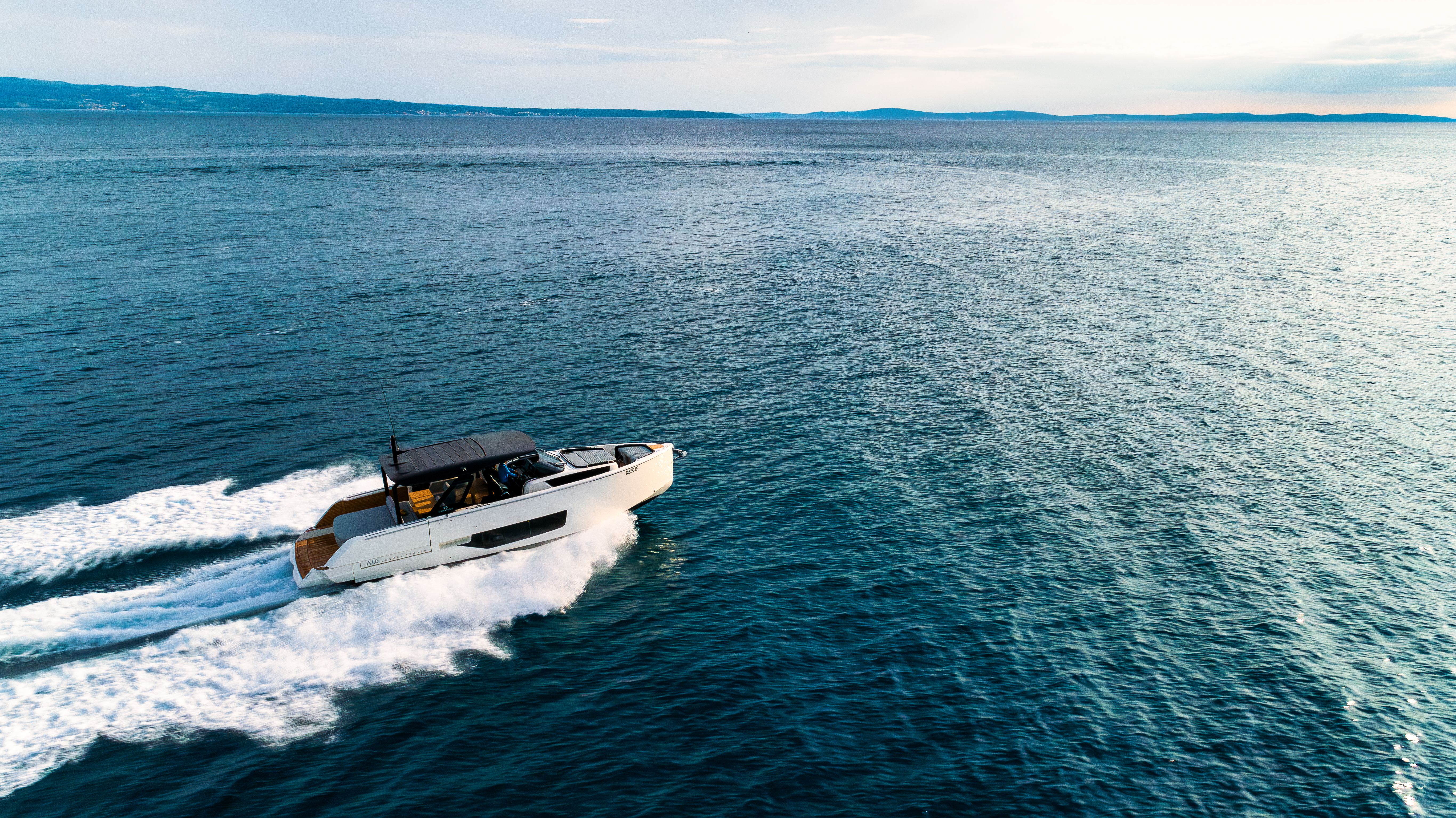 Cranchi A46 luxury boat speeding on the ocean, creating a foam trail behind it.