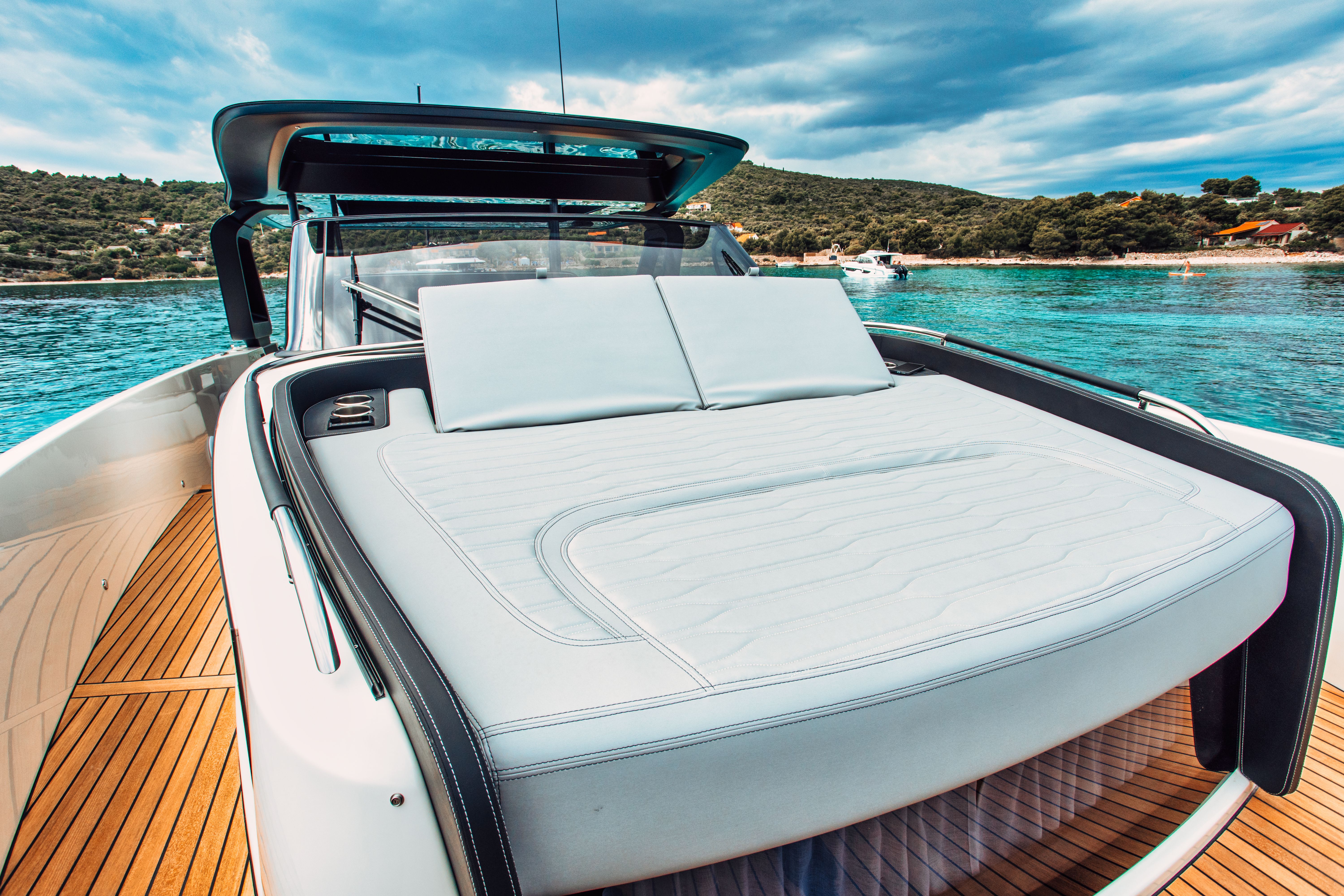 Close-up of a sunbathing area on Cranchi A46 boat, featuring plush cushions and a wooden deck.