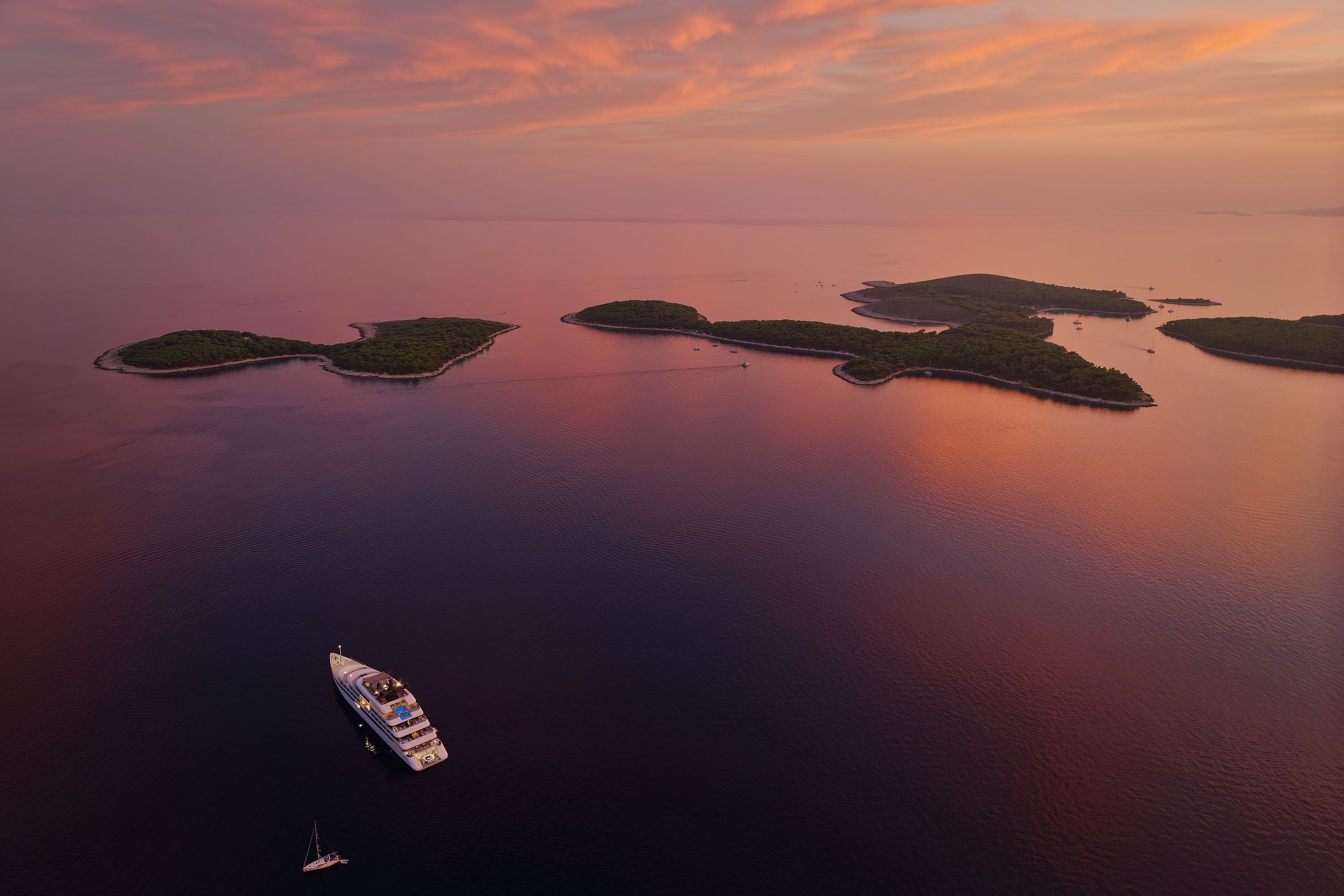 Aerial view of Hvar archipelago at sunset with colorful sky and calm waters.