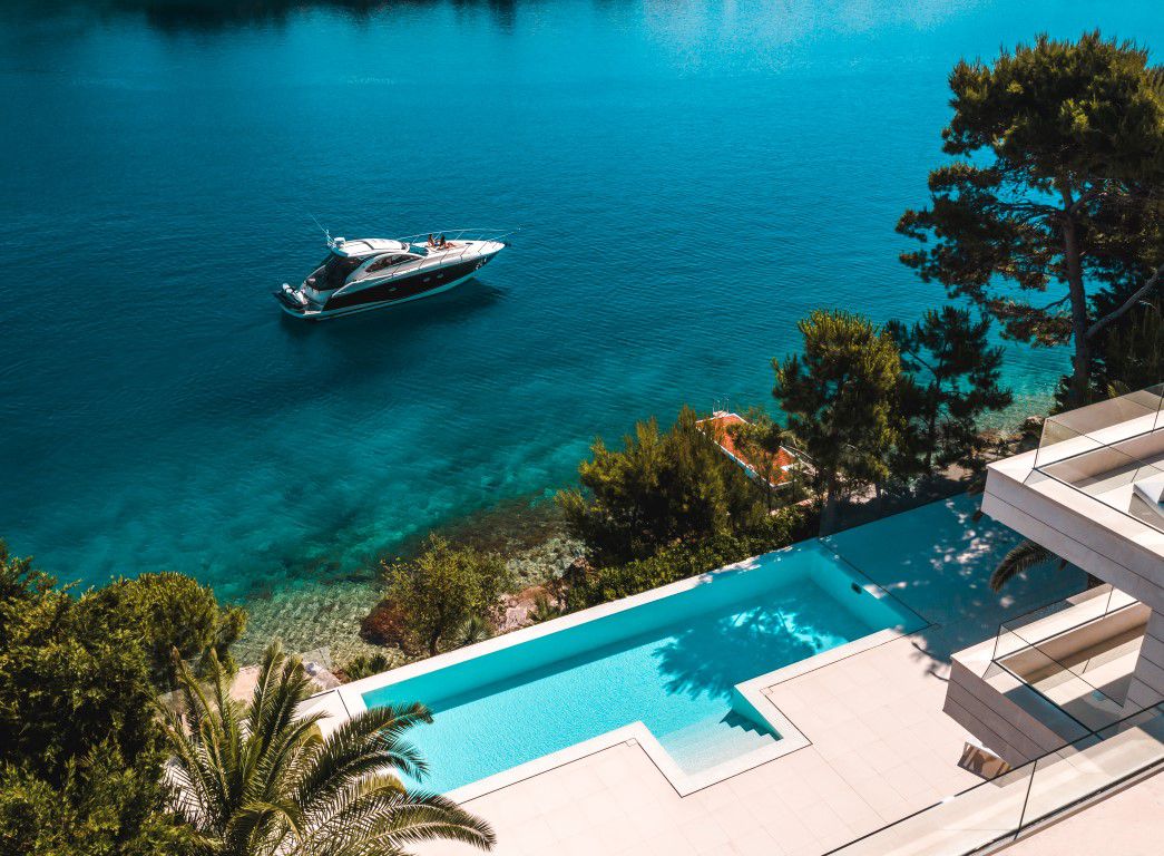 View of a beachfront Villa Dolce Vita Selca with an infinity pool beside a boat in clear blue water