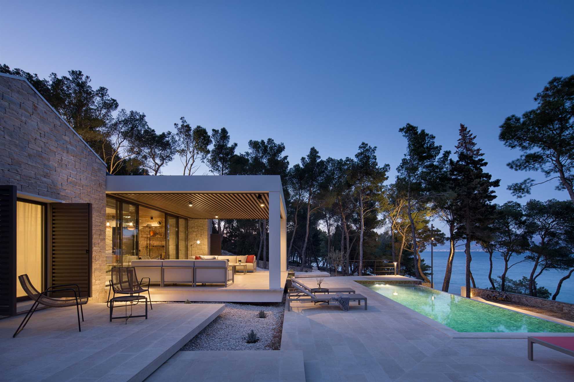 Evening view of a modern Villa Sutivan Exclusive with a pool, surrounded by trees and near the beach