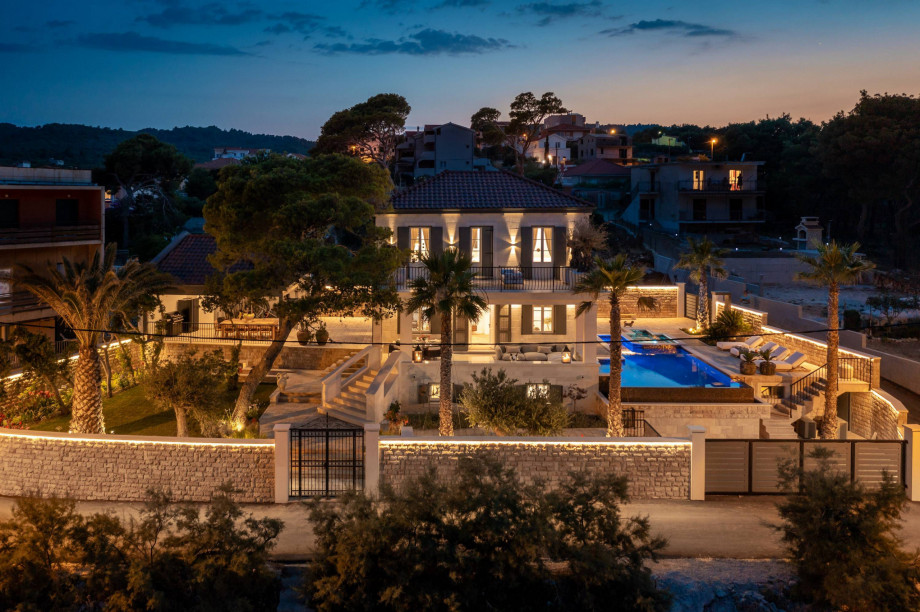 A stunning luxury Villa Skyline Trogir featuring a swimming pool surrounded by lush palm trees