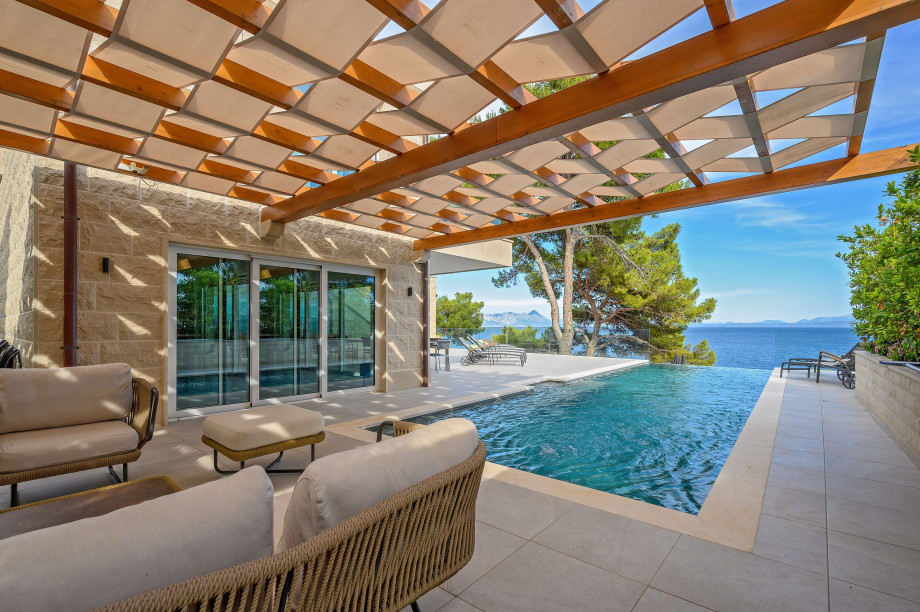 A serene pool and patio area of Villa Blanc Brac featuring elegant furniture, overlooking a stunning sea view.