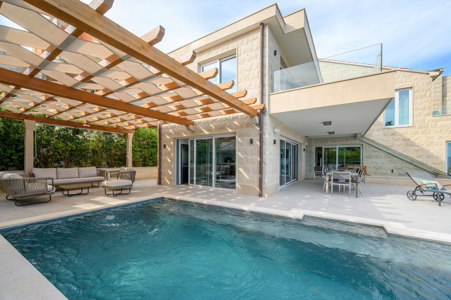 A serene pool and patio area in Villa Blanc Brac featuring a stylish pergola overhead, perfect for relaxation and outdoor gatherings.