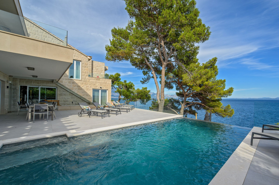 A spacious pool and patio area in Villa Blanc Brac overlooking the serene sea, perfect for relaxation and leisure activities.