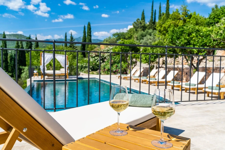 The pool at Villa Aurora Dubrovnik framed by mountains, with sunbeds, showcasing a peaceful retreat in Dubrovnik.