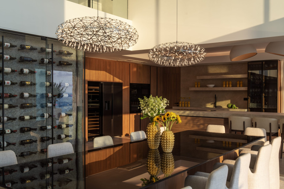 Elegant kitchen and wine bar at Villa Isabella, featuring a stunning wall of wine bottles, dining table and white chairs