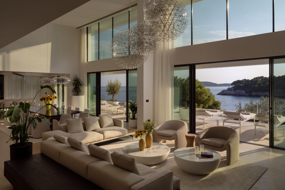 Elegant living room of Villa Isabella Dubrovnik, featuring large windows that open to a terrace with sunbeds and stunning sea views