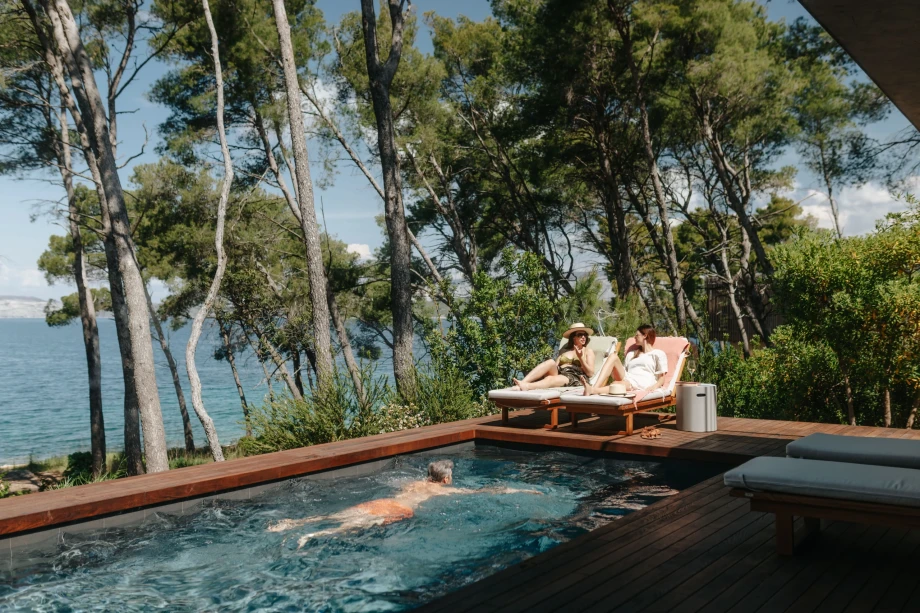 Beachfront villa on the island of Hvar with pool and people swimming and sunbathing on the pool terrace
